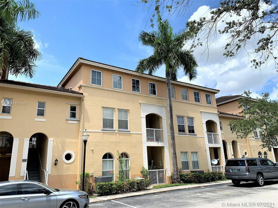 Front view of a multi-story residential building with balconies and large windows.