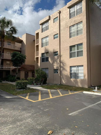 Front view of a multi-story residential building with parking area.