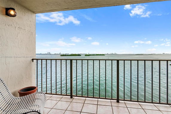 Balcony view overlooking a large body of water with distant buildings and islands visible.
