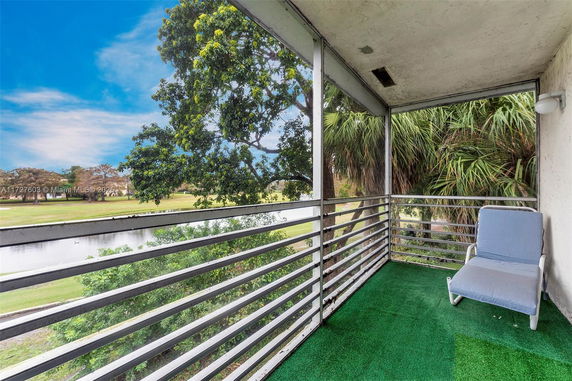View from a balcony showing trees and a water body in the surroundings.