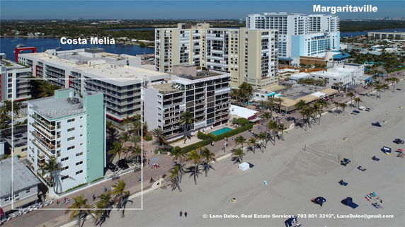 Aerial view of beachfront buildings with a surrounding promenade and people enjoying the beach.