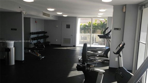Interior view of a gym area with fitness equipment and large windows.