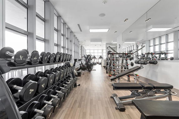 Interior view of a gym with exercise equipment and weights lined up.