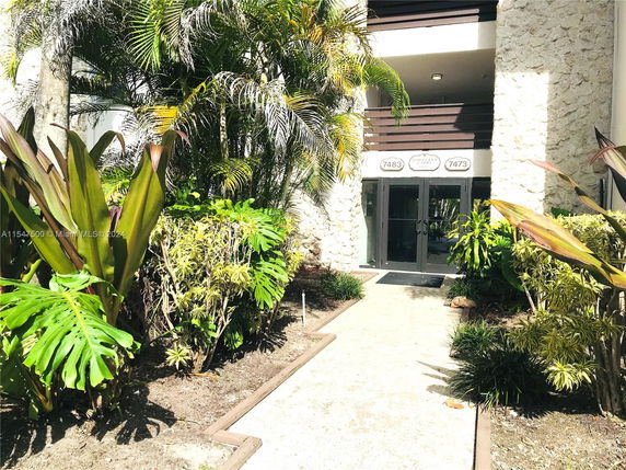 Front view of a building entrance with surrounding plants.