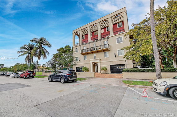 Front view of a multi-story residential building with arched balconies and garage entrances.