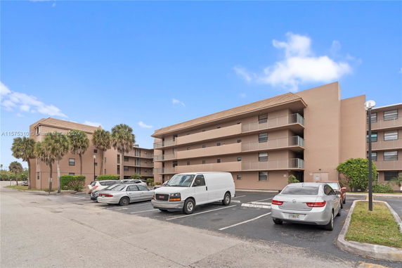 Front view of a multi-story apartment building with a parking lot.