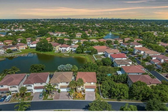 Wide aerial view of a suburban neighborhood with multiple houses and greenery.