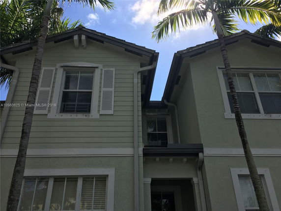 Front view of a two-story house with green siding and multiple windows.