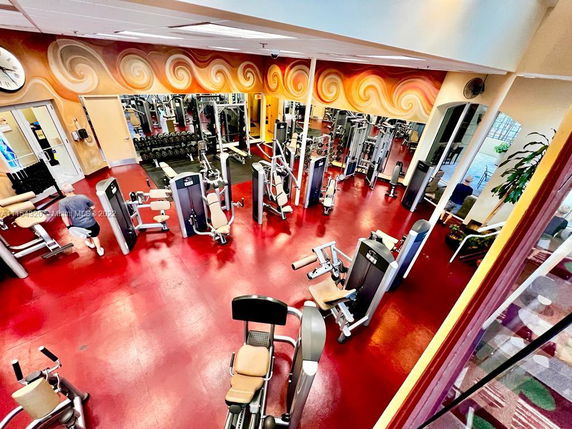 Interior view of a gym area with various fitness equipment and a colorful wall mural.