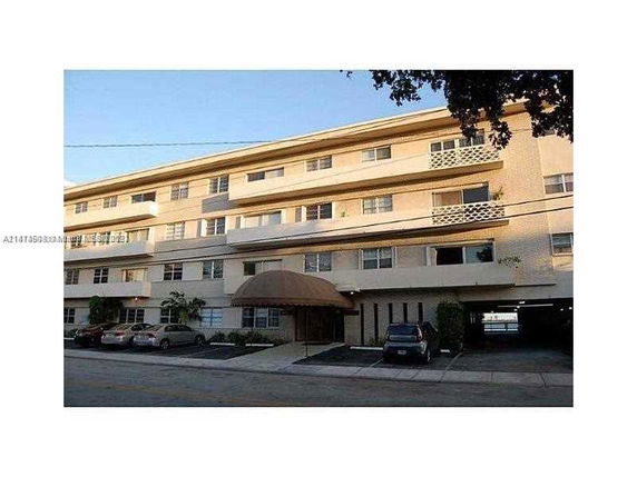 Front view of a multi-story residential building with parking area.