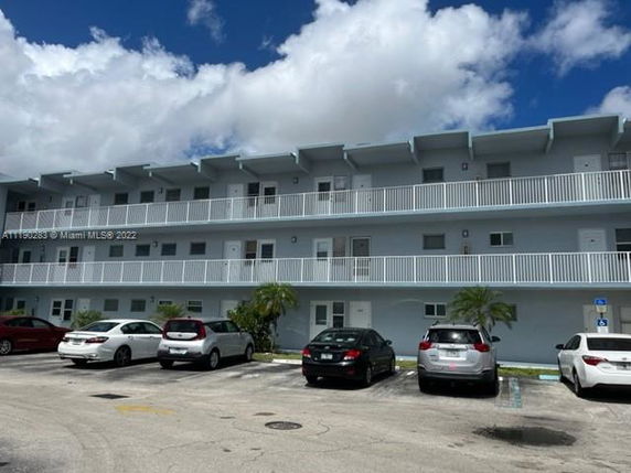 Front view of a multi-story apartment building with balconies and parking area.