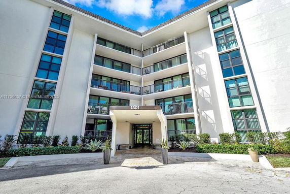 Front view of a multi-story apartment building with balconies and large windows.