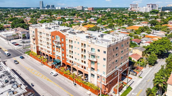 Front view of a multi-story residential building with balconies, adjacent to a street.