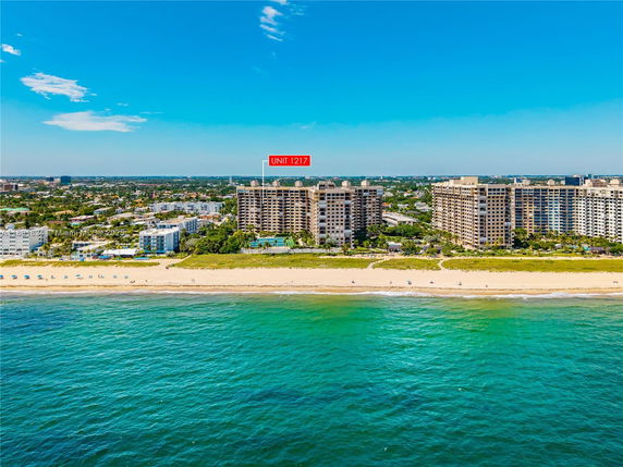 Aerial view of beachfront buildings with ocean and beach in the foreground.