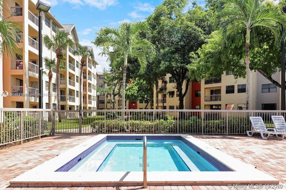 Outdoor area with a small swimming pool in front of a multi-story residential building.