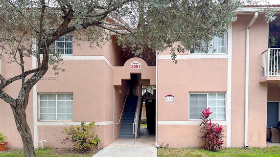 Front view of a peach-colored apartment building with an exterior staircase.