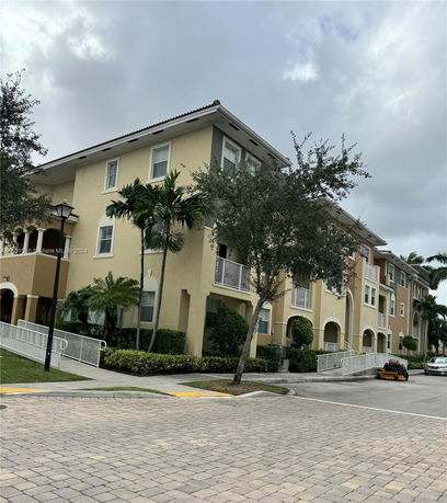Front view of a multi-story residential building with balconies and arched entrances.