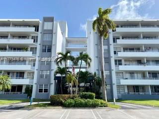 Front view of a multi-story building with balconies and palm trees.