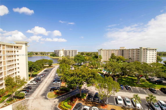 Panoramic view of multiple apartment buildings with surrounding greenery and a parking lot.