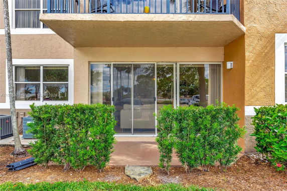 Front view of a multi-story building with sliding glass doors and a small patio area.