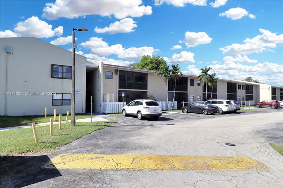 Front view of a two-story apartment building with parking space.