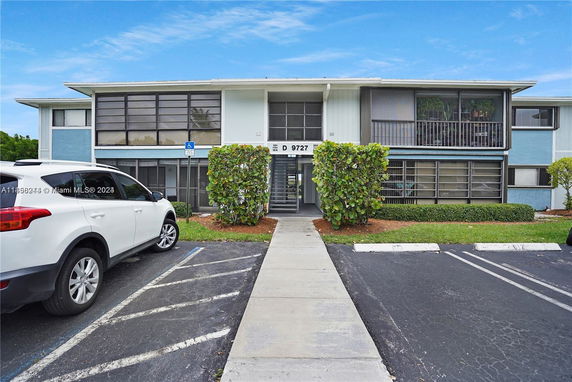 Front view of a two-story apartment building with parking spaces.