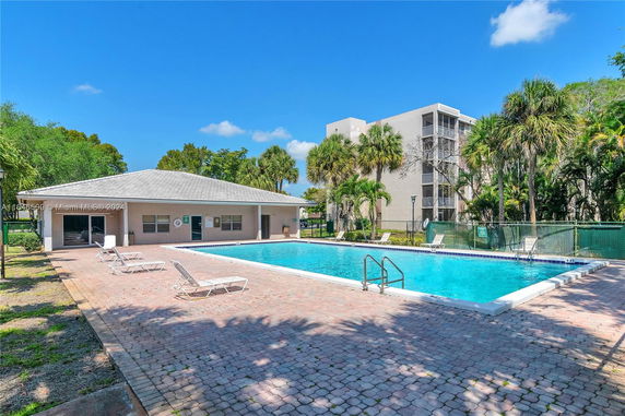 Outdoor swimming pool with surrounding seating area and adjacent building.