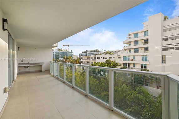 View from a balcony towards nearby modern buildings and greenery.
