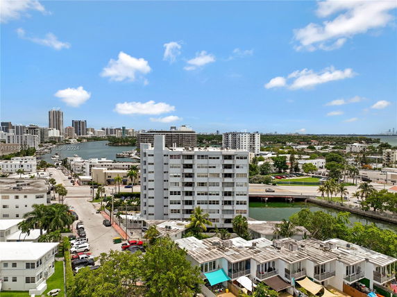 Panoramic view of a cityscape with a mid-rise apartment building, water, and distant skyline.