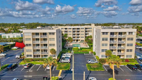 Front view of a multi-story building complex with balconies and a central courtyard pool.