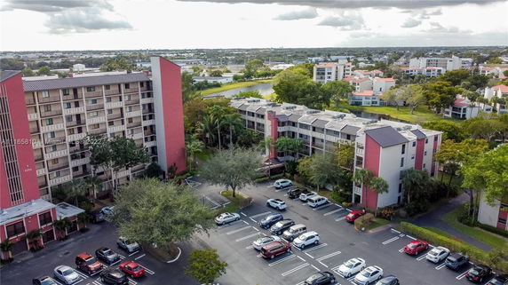Aerial view of a multi-story residential building with a parking area in front.