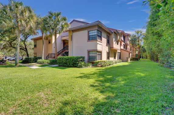 Front view of a two-story residential building with a landscaped lawn and surrounding greenery.