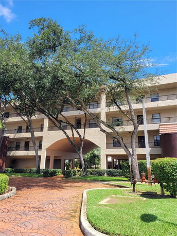 Front view of a multi-story building with balconies and an arched entrance.