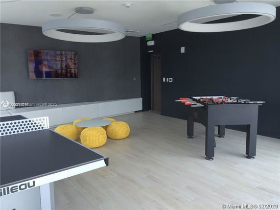 Interior view of a recreation room with table tennis, foosball table, and seating area.