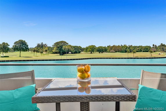 Balcony view overlooking a body of water and golf course with trees in the distance.
