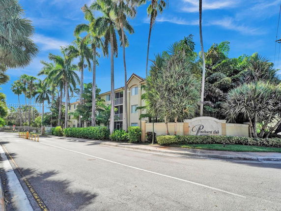 Front view of a multi-story residential building with palm trees.