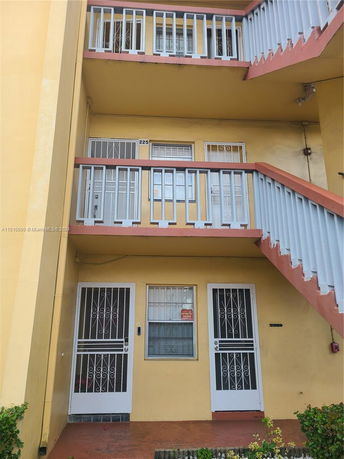 Front view of a multi-story building with staircase and balcony.