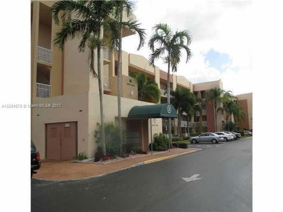 Front view of a multi-story apartment building with balconies and a covered entrance.