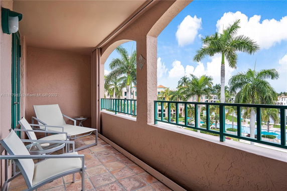 Balcony view overlooking a pool area with palm trees in a resort setting.