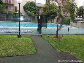 Outdoor swimming pool area surrounded by a fence and pathway.