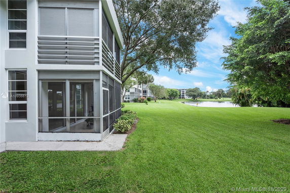 Corner view of a building with large windows and an outdoor grassy landscape extending to a pond.