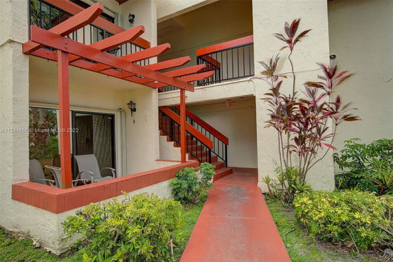 Outdoor view of a building entrance with a red pergola and stairs.