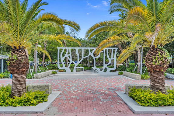 Outdoor area with palm trees and a decorative structure.