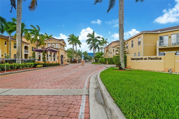 Front view of a multi-story residential building with palm trees and a paved driveway.