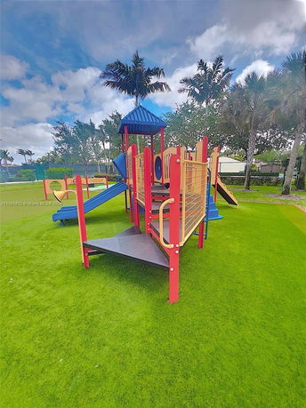 Outdoor play area with colorful playground equipment and slides on grassy field.