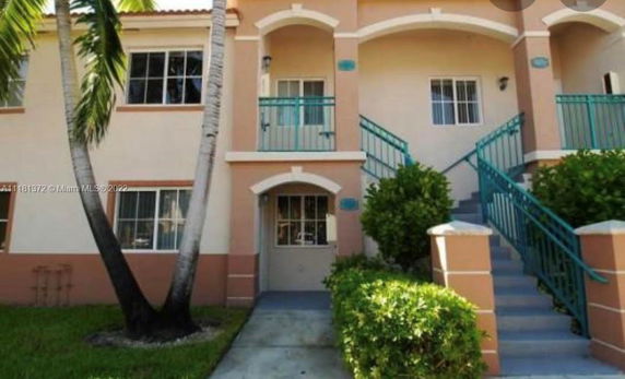 Front view of a multi-level apartment building with staircases leading to the upper floor.