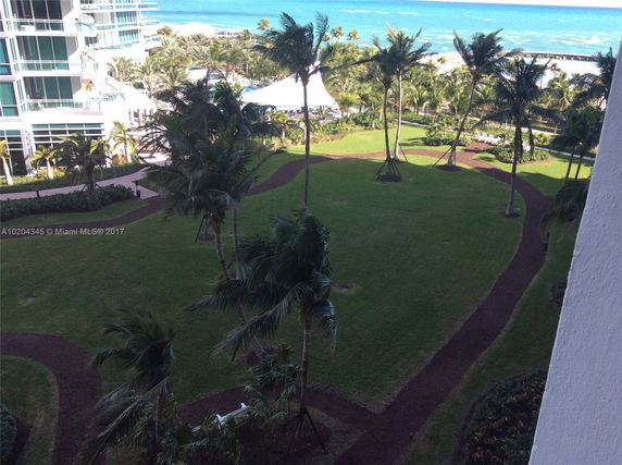View of landscaped gardens and pathways near a beachfront building.