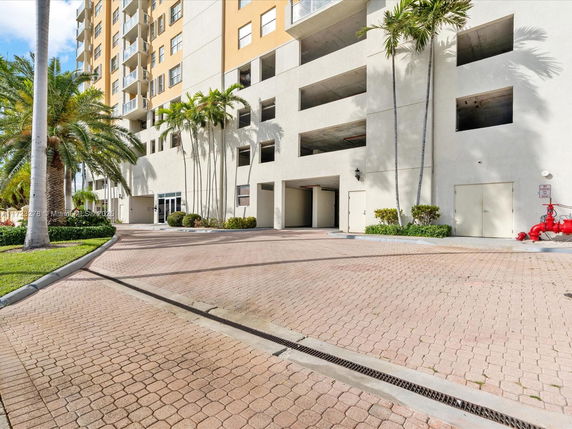Front view of a multi-story building with balconies and palm trees.
