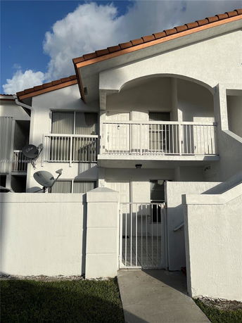 Front view of a two-story house with a white facade and balcony.