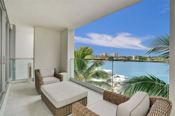 Covered balcony with seating offering a view of water and distant buildings.